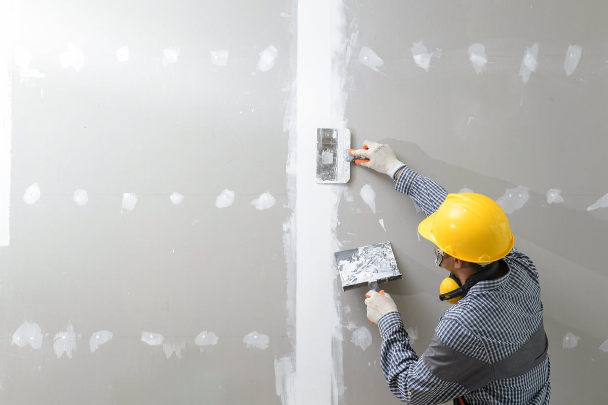 Professional contractor plastering and finishing drywall walls in modern home construction