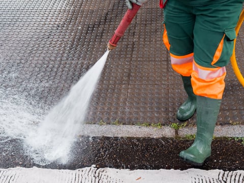 Worker power washing sidewalk