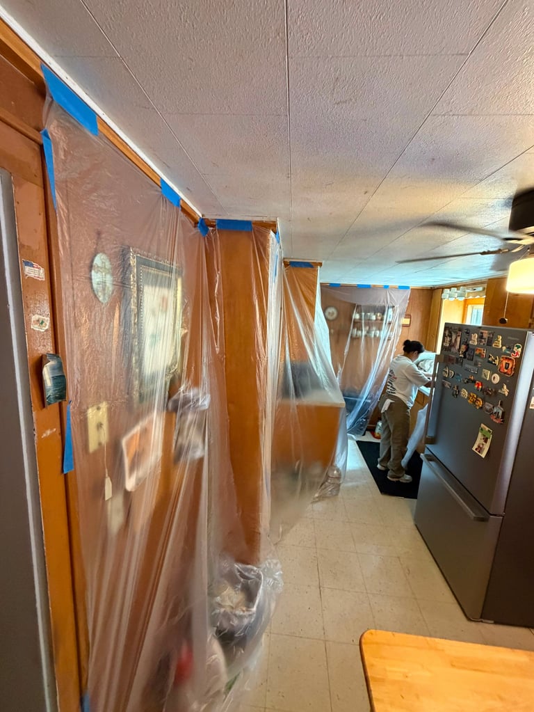 Kitchen appliances wrapped in plastic sheeting and blue painters tape during renovation or painting project